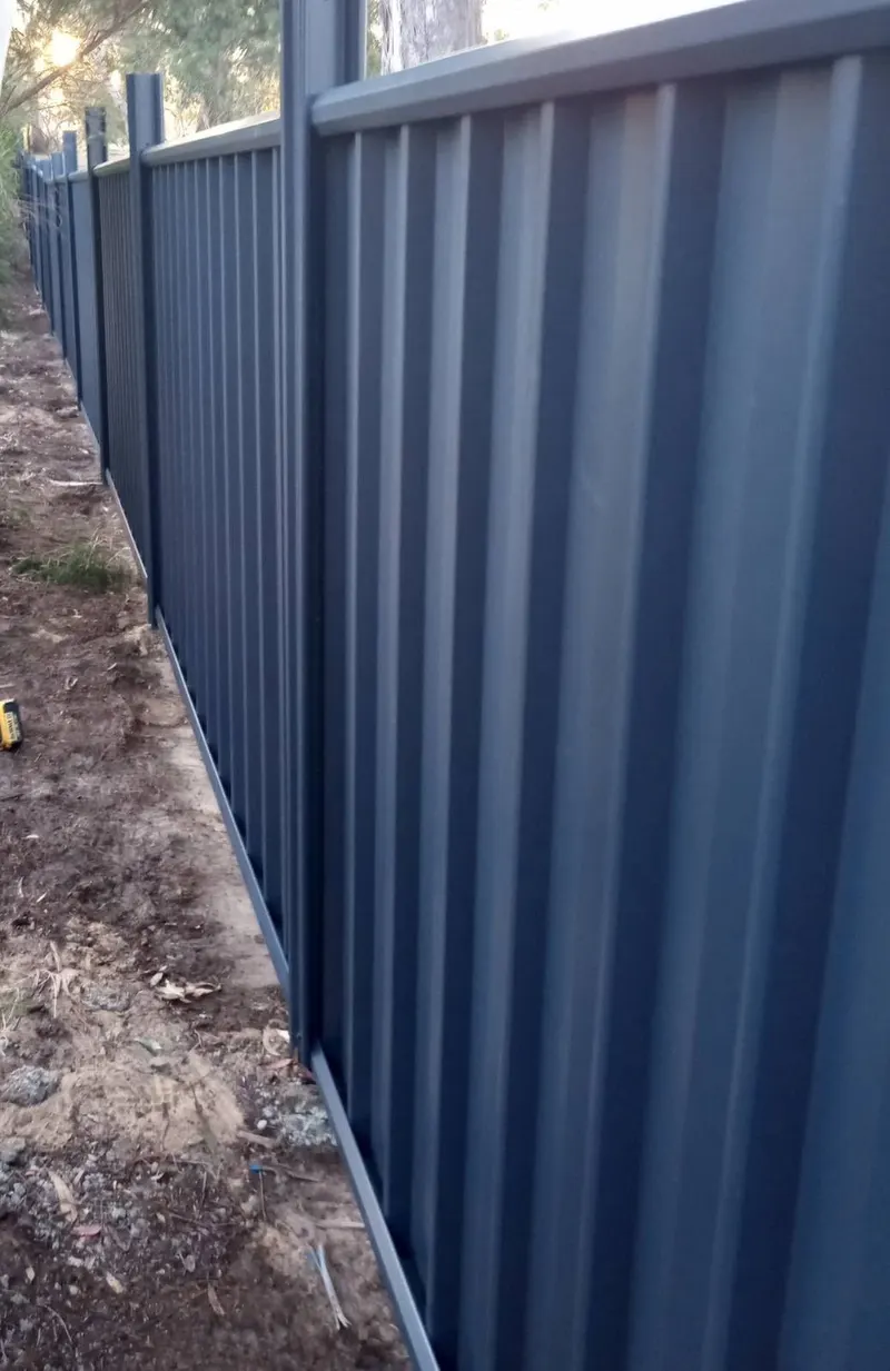 A long dark grey Colorbond fence finished along a boundary