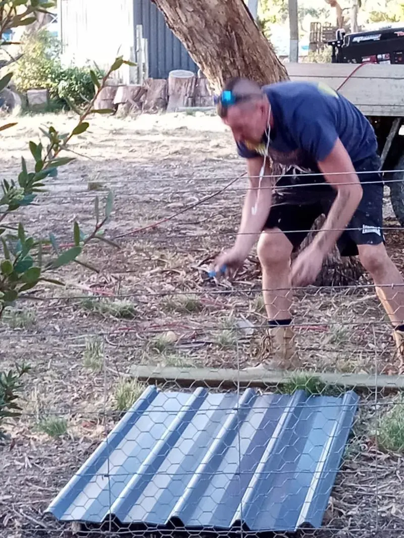 The owner of Tasmania Fencing measuring a Colorbond sheet on site