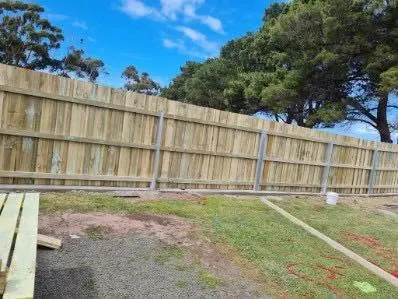 Finished timber fence along a lawn with gum trees behind