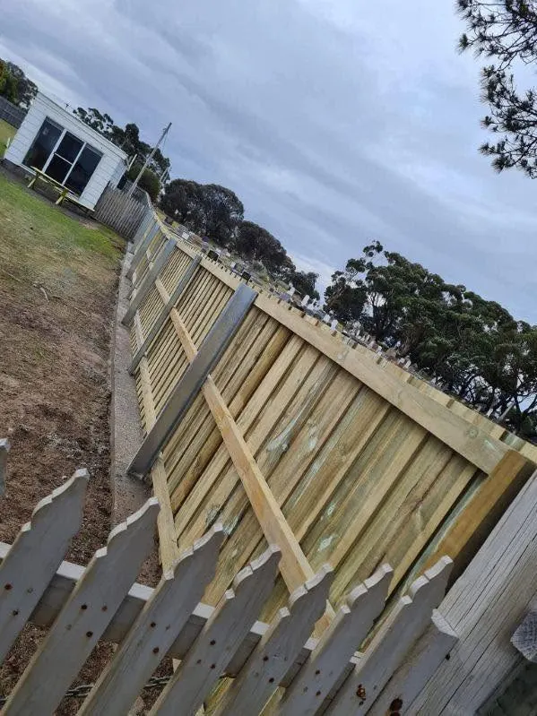 A new timber fence going up beside an old picket fence