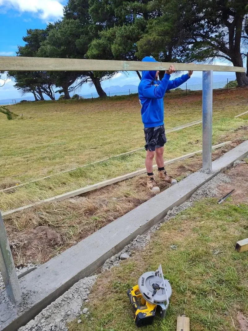 Fitting the top rail between steel posts on a grassy block